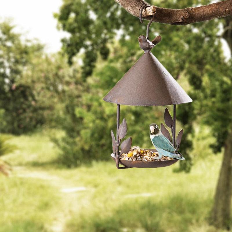 Iron Aviary Bird Feeder on a porch surrounded by greenery