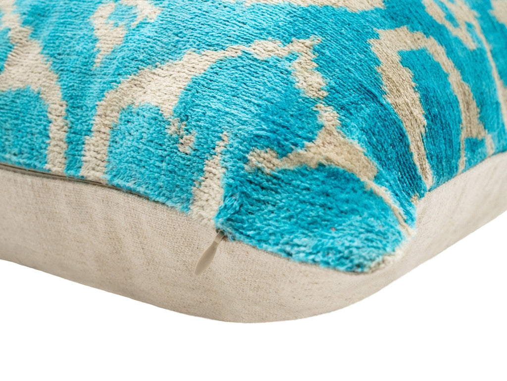 Lifestyle image of the turquoise Ikat velvet pillow on a stylish bed